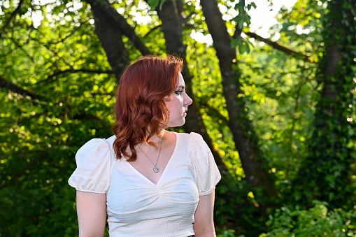 Portrait of a young redhead  girl in green nature, looking to the side