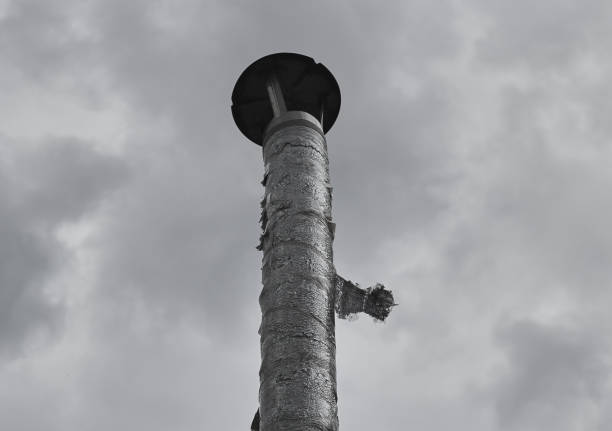 Metal chimney pipe against gray sky