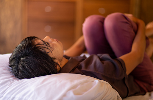 Depressed, contemplative woman lying on pillow in bed