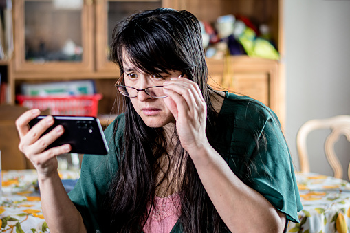 In these shots, the woman is shown adjusting her glasses to get a better look at her device's screen, demonstrating her awareness of cybersecurity threats and her willingness to take action to protect herself. The candid, non-posed approach captures the woman's sense of vigilance and the importance of attention to detail in confronting online dangers.