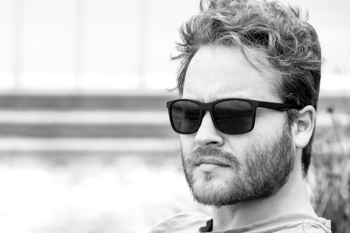 Black and white portrait of 26 years old young man with sunglasses, background with copy space, full frame horizontal composition