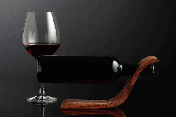 黒い反射背景に木製のボトルホルダーに入った赤ワインのボトル。 - wine wine rack winery black ストックフォトと画像