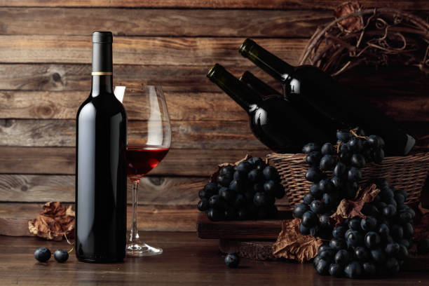 istock Red wine and blue grapes on an old wooden table. 1472161014