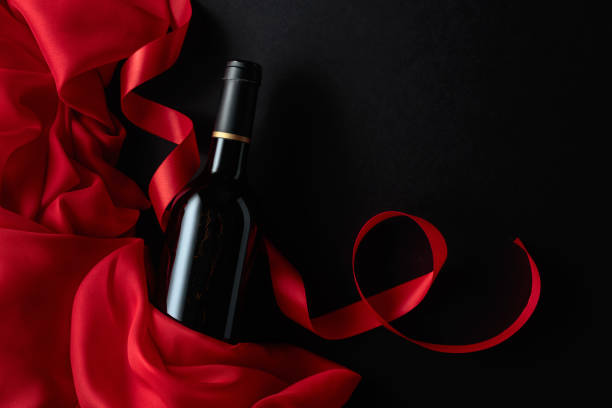 istock Bottle of red wine with red satin on a black background. 1472161045