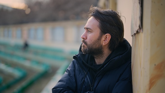 A profile view waist up portrait of a man outdoors.