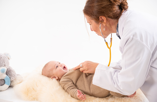 Beautiful doctor examining newborn  baby boy on a white background