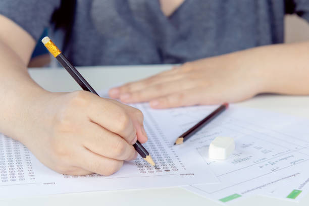 istock Students hand holding pencil writing selected choice on answer sheets and Mathematics question sheets. students testing doing examination. school exam 1472161711