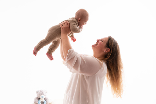 Portrait of happy smiling mother and baby boy playing together over a white background