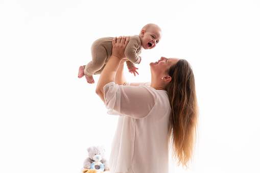 Portrait of happy smiling mother and baby boy playing together over a white background
