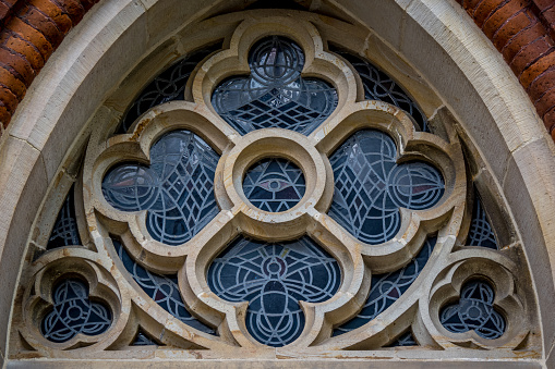 Gothic rose window of St. Johann church in Bremen Schnoorviertel with an all-seeing eye at its center and a peace dove in the bottom glass elements, showcasing its historic and religious significance.