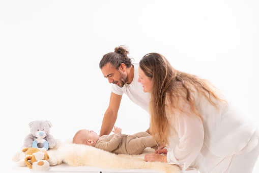 Happy Caucasian family with a newborn baby boy in the bedroom. White light home inter
