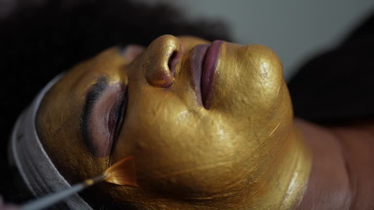 Beautician applying facial mask in a woman at a beauty spa