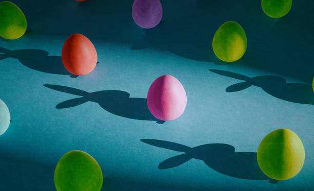 istock Trendy pattern made of colorful eggs with funny rabbit shadow on dark moody blue cardboard. Easter concept for design templates or greeting card. 1472168891