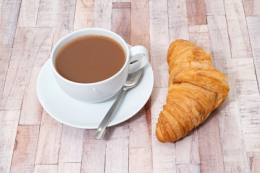 Breakfast items of a fresh croissant with a cup of tea