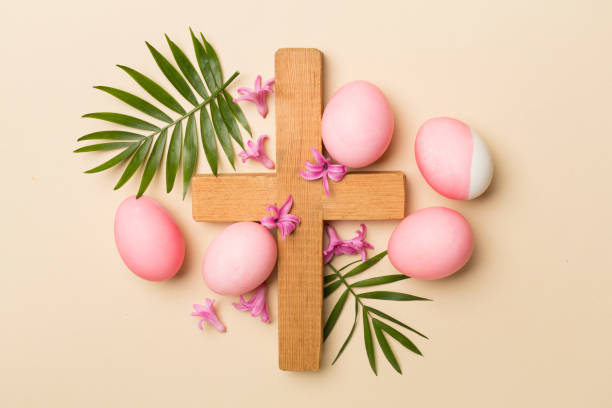istock Pink Easter eggs with cross and palm leaves on color background, top view 1472169470