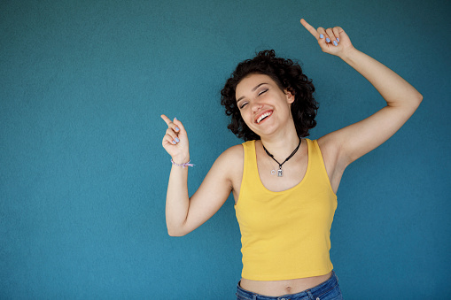 Young happy woman dancing against blue background