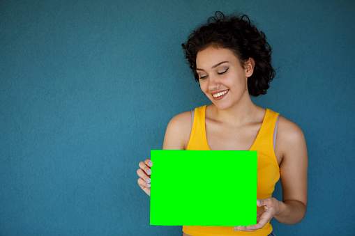 Young woman holding blank green paper