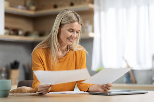 istock Happy blonde woman freelancer working from home, reading papers 1472174845