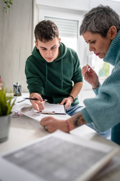 One student teenage caucasian man study learn with help of his tutor professor or mother senior woman at home having private lesson to prepare for exam education concept real people copy space stock photo