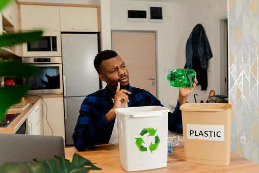 Portrait of a young man recycling plastic waste from his home