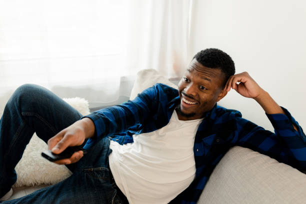 istock Young man enjoying on the sofa, watching TV 1472177958