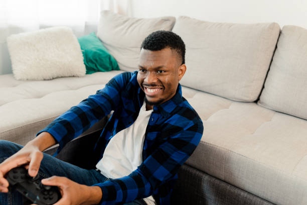 istock Young man gaming and having fun at home 1472177975