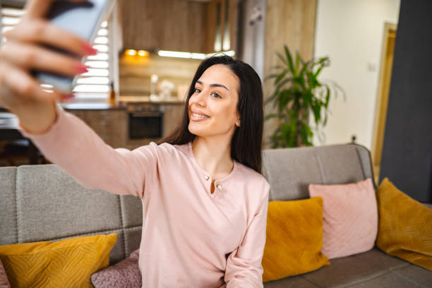 istock Young woman taking selfies while sitting on a sofa at home 1472179082