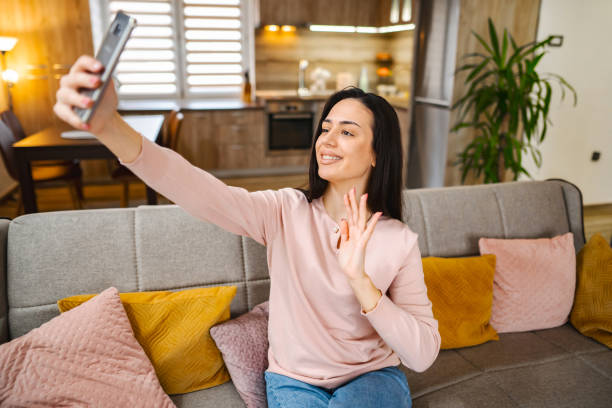 istock Young woman talking on a video call while sitting on a sofa at home 1472179159