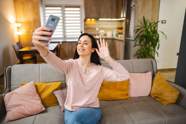 istock Young woman talking on a video call while sitting on a sofa at home 1472179194