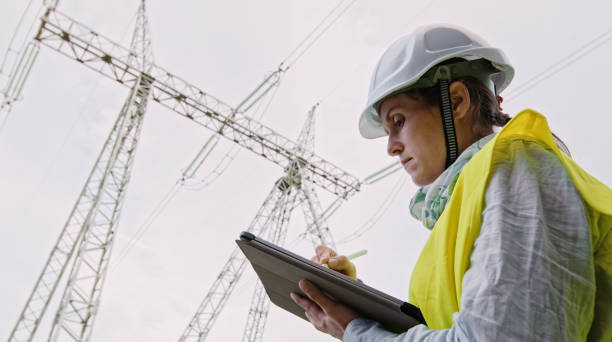 istock High voltage female engineer working on the field. 1472187796