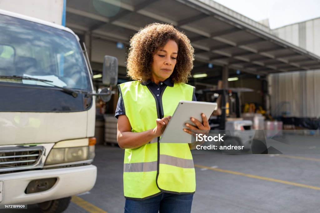 Woman supervising the dispatch of trucks at a distribution warehouse African American woman supervising the dispatch of trucks at a distribution warehouse Freight Transportation Stock Photo