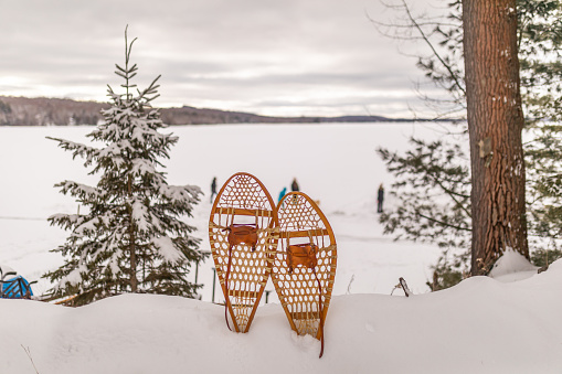 A landscape view of a frozen lake up north with the focus on a pair of rustic snowshoes