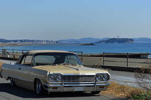 An old American car, the coast and Enoshima.\nChigasaki Southern Beach Coast, Chigasaki City, Kanagawa Prefecture, Japan.
