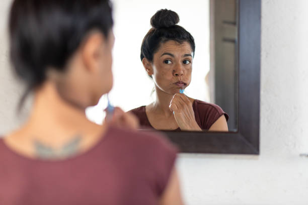 Woman brushing teeth in front of mirror