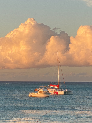 Two boats in intimate distance on calm waters with large puffy clouds overhead