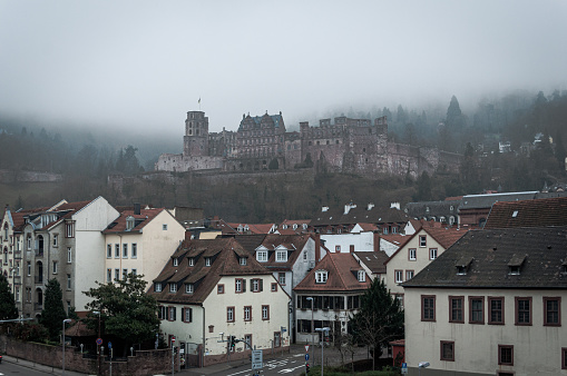 Heidelberg, Germany - Dec 26, 2018 - couple of ancient houses in the central part of the city with a castle in the fog on the background