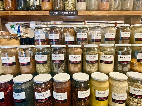 Horizontal shelves of glass jars with health and healing micronutrient medicinal superfoods, powders, teas, herbs & spices in whole foods store Byron Bay NSW Australian