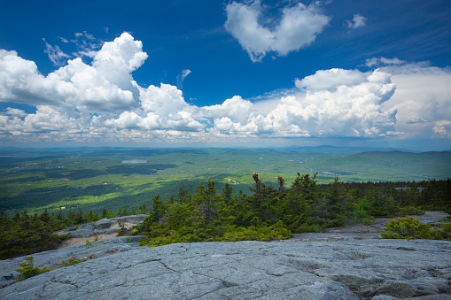 White clouds in a deep blue sky over the summit of Mt. Kearsarge in Wilmot, New Hampshire on a sunny summer day.