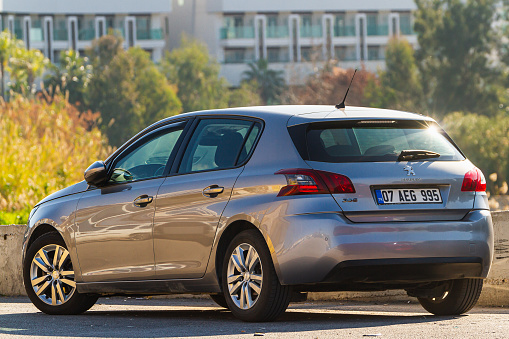 Side, Turkey -January 23, 2023:    silver Peugeot 308    is parked  on the street on a warm day against the backdrop of a   park, fence