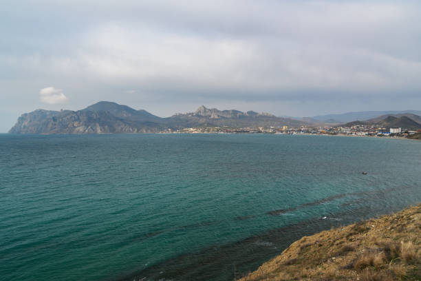 View of seaside resort city Koktebel , mountain Kara Dag from hill in spring. Crimea View of seaside resort city Koktebel , mountain Kara Dag from hills in spring. Crimea feodosiya stock pictures, royalty-free photos & images