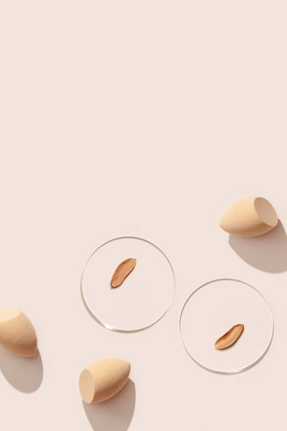 istock Beauty blender make up sponge for foundation cream, samples on glass disk, sponges on beige color background with hard light. Skincare beauty product. Swatches from tone cream and makeup puff 1472220155