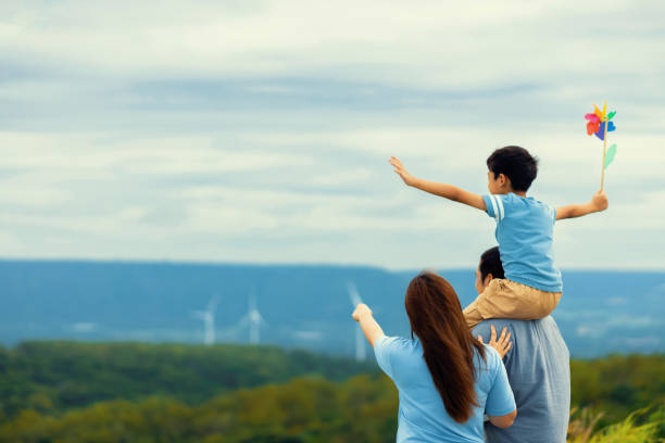 fortschrittliche glückliche familie genießt ihre zeit im windpark für grünes energiekonzept. - fuel and power generation power wind power supply stock-fotos und bilder