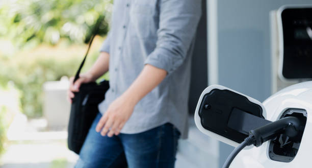 istock Focus EV charging station at home with blur progressive man in background. 1472223153