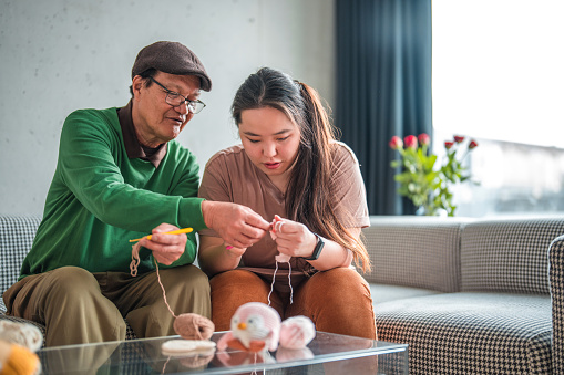 Happy Asian Family Doing Crochet Together At Home