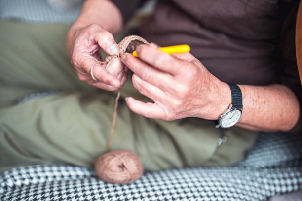Mature Asian man doing crochet at home. He is enjoying learning new skills during his early retirement.