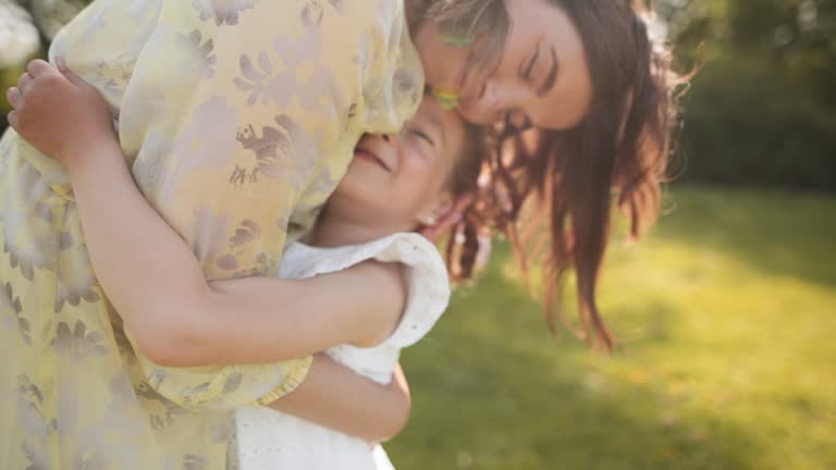 Happy cute girl runs to mother, with eyes closed charming little baby daughter hugs mom, hugs, enjoys tender sweet moment concept, close up.  Family walking in the park in nature