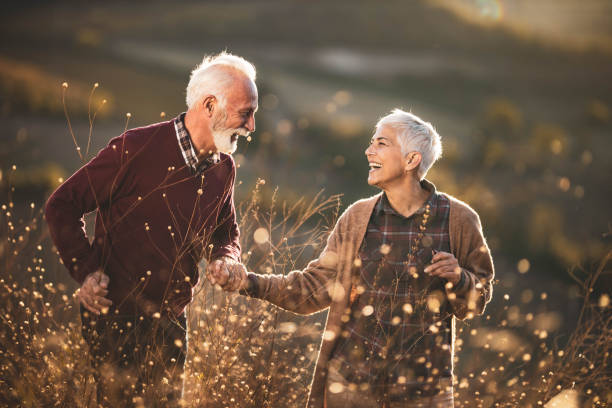 istock Cheerful mature couple talking while walking through tall grass in nature. 1472240258