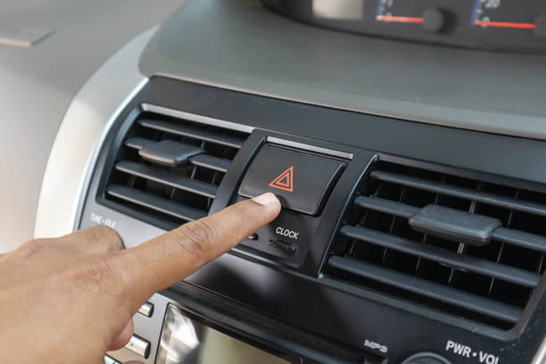 車の非常灯ボタンを指で叩き、赤い三角形の車の危険警告ボタンを押す男。 - fog light switch ストックフォトと画像