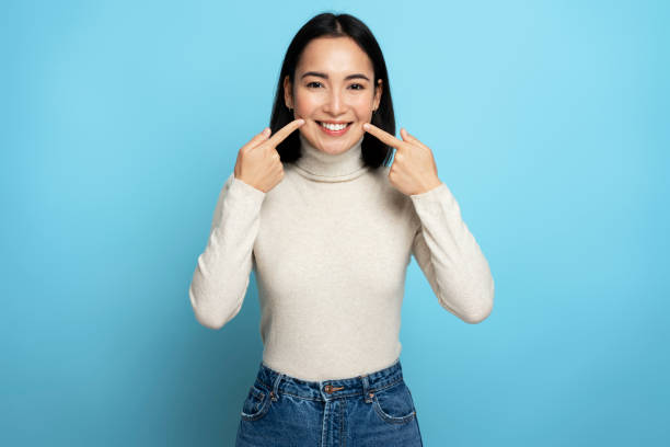 portrait of pretty cheerful woman points index fingers at smile shows white teeth - human mouth imagens e fotografias de stock