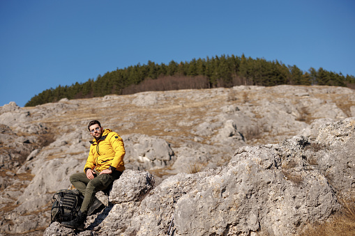 Young man sitting and resting from hiking on rocky mountain